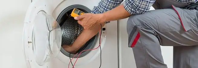 Dryer repair technician inspecting and repairing a clothes dryer in Bakersfield, CA