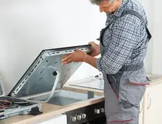 Appliance repair technician installing a built-in cooktop in Bakersfield, CA