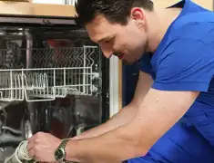 Dishwasher repair technician inspecting and servicing an open dishwasher in Bakersfield, CA