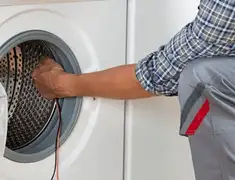 Dryer repair technician diagnosing and servicing a clothes dryer in Bakersfield, CA
