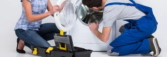 Washer repair technician inspecting a front-load washing machine with tools in Bakersfield, CA