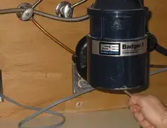 Garbage disposal repair technician tightening the mounting ring under a sink in Bakersfield, CA