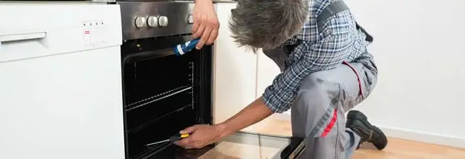 Oven repair technician inspecting and servicing an electric oven in Bakersfield, CA
