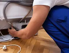 Appliance repair technician fixing refrigerator water line and connections in Bakersfield, CA