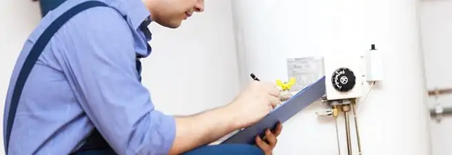 Water heater repair technician inspecting the unit and recording service notes in Bakersfield, CA