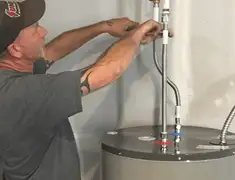 Water heater repair technician tightening supply line connections in Bakersfield, CA