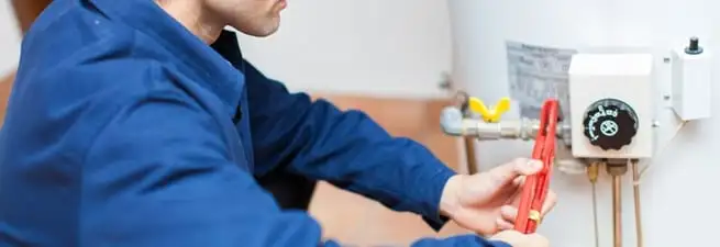 Water heater repair technician adjusting the temperature control and gas valve in Bakersfield, CA